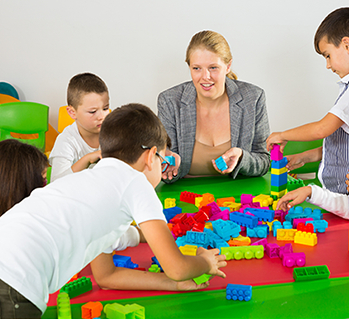 kids playing with blocks along with a woman sitting with them