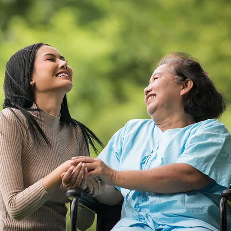 Caregiver with an old lady holding hands and having a good laugh