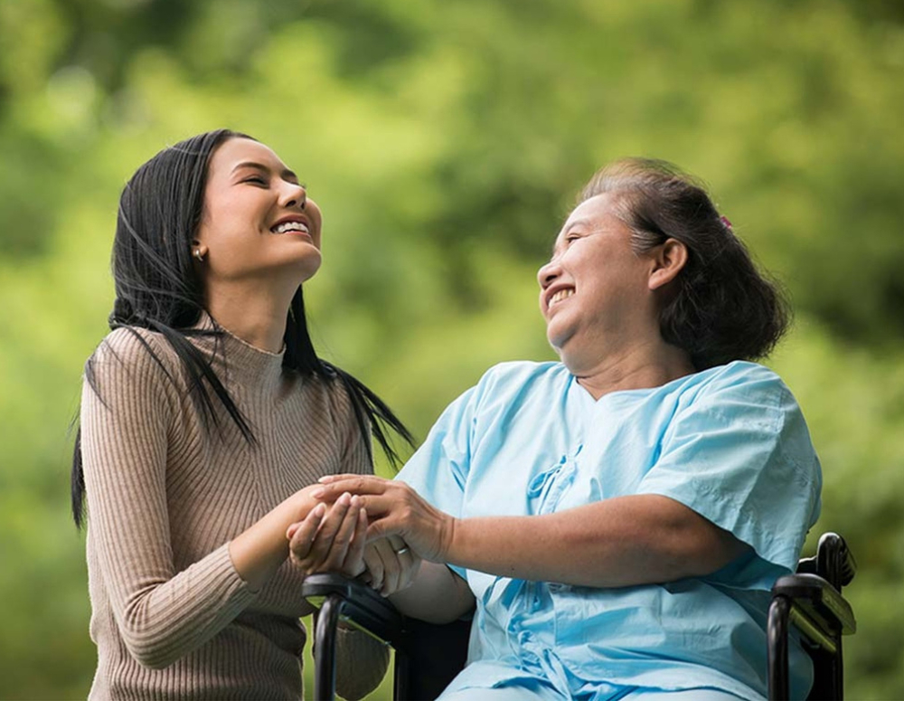 Caregiver with an old lady holding hands and having a good laugh