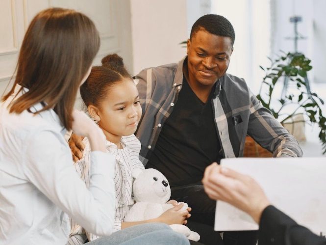 Kid having therapy while sitting with her parents around