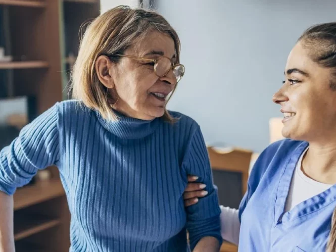 Nurse talking to an old lady while helping her to walk