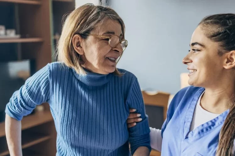 Nurse talking to an old lady while helping her to walk Nurse talking to an old lady while helping her to walk