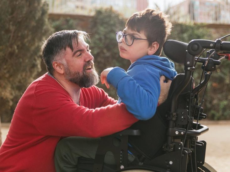 Man taking care of a handicapped boy, sitting on a wheelchair