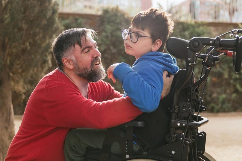 eqc-pediatric-homecare Man taking care of a handicapped boy, sitting on a wheelchair