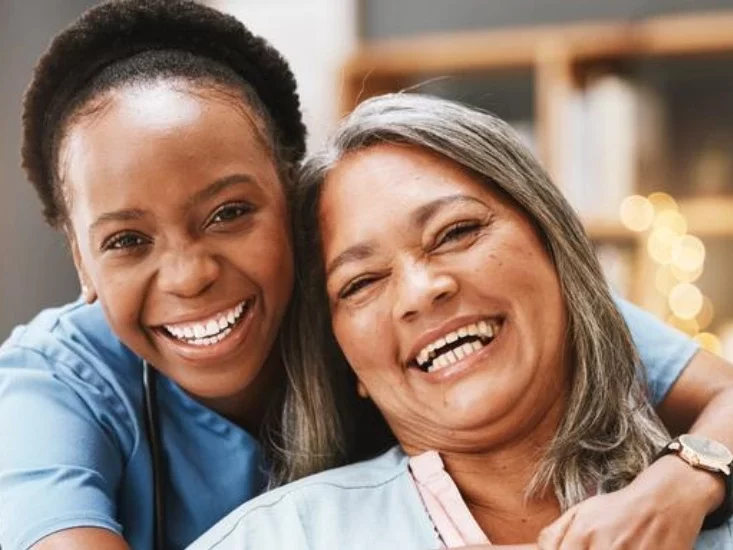 Nurse hugging an old lady while they smile