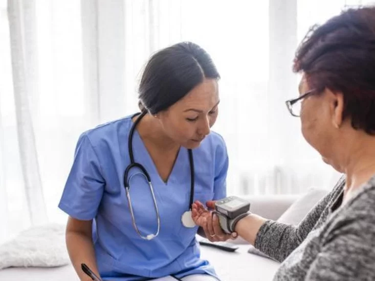 nurse checking an old women's blood pressure