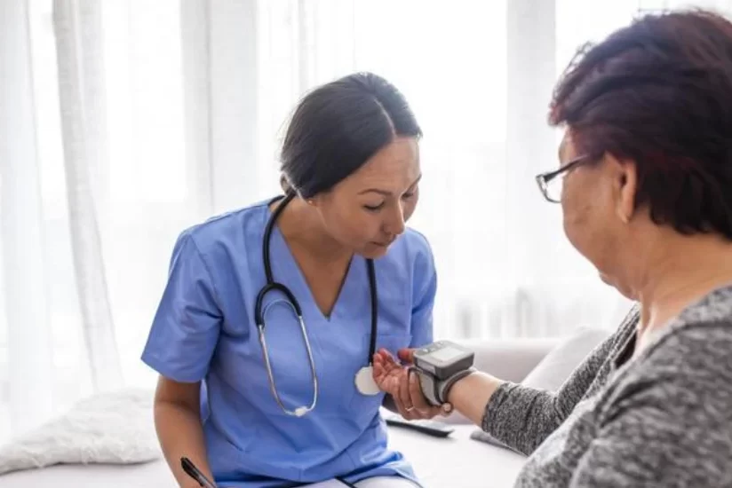 nurse checking an old women's blood pressure