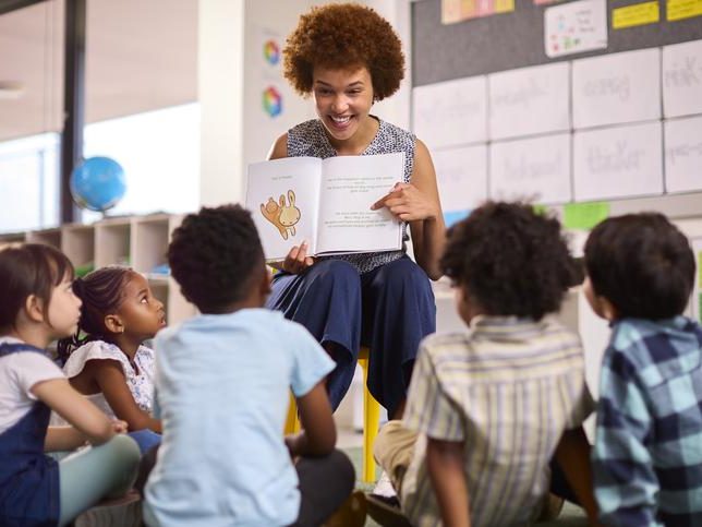 A school teacher with a bunch of students sitting in a school's classroom
