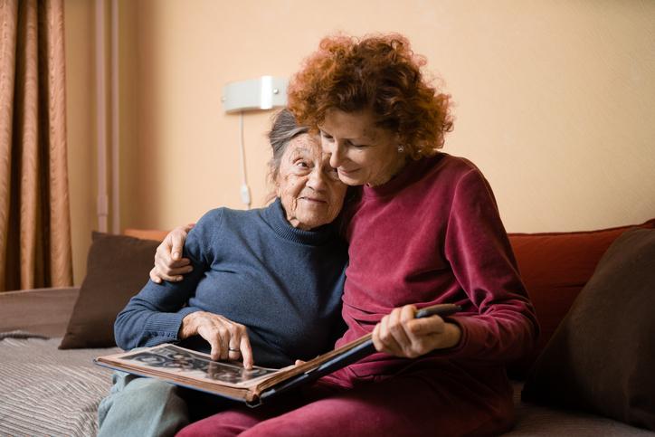 senior-sitting-with-homecare-staff A woman showing some photos in an album to a senior old woman