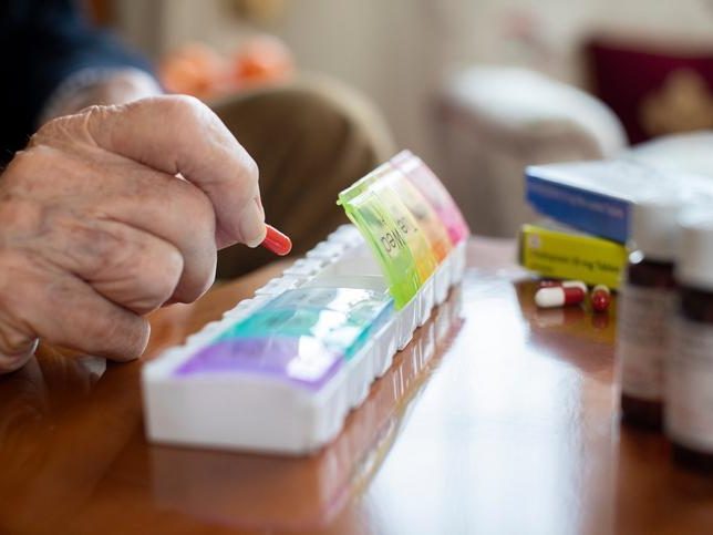 Old man having medicine from his medication box