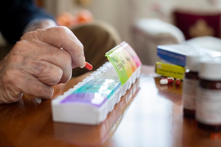 Holiday Medication Management Old man having medicine from his medication box
