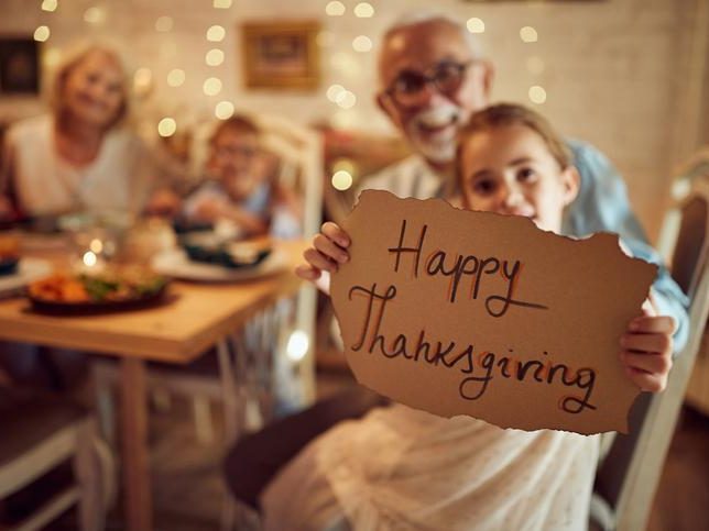 Old man and his granddaughter holding Happy thanksgiving small banner