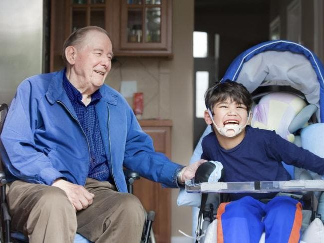 An old man and an adult boy who is dependent sitting and smiling together