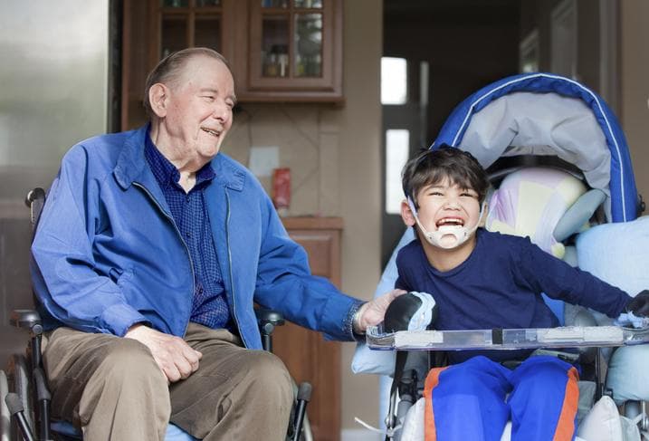 inhome-care-for-all-ages An old man and an adult boy who is dependent sitting and smiling together