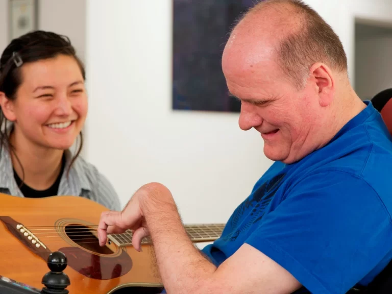 special person playing guitar in care of home care lady
