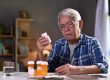 Old man looking at the details written on medicine bottle