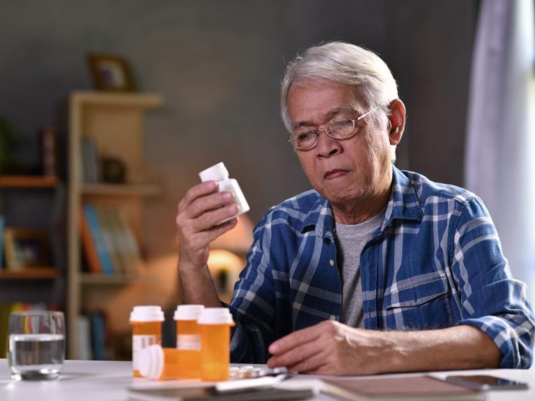Old man looking at the details written on medicine bottle
