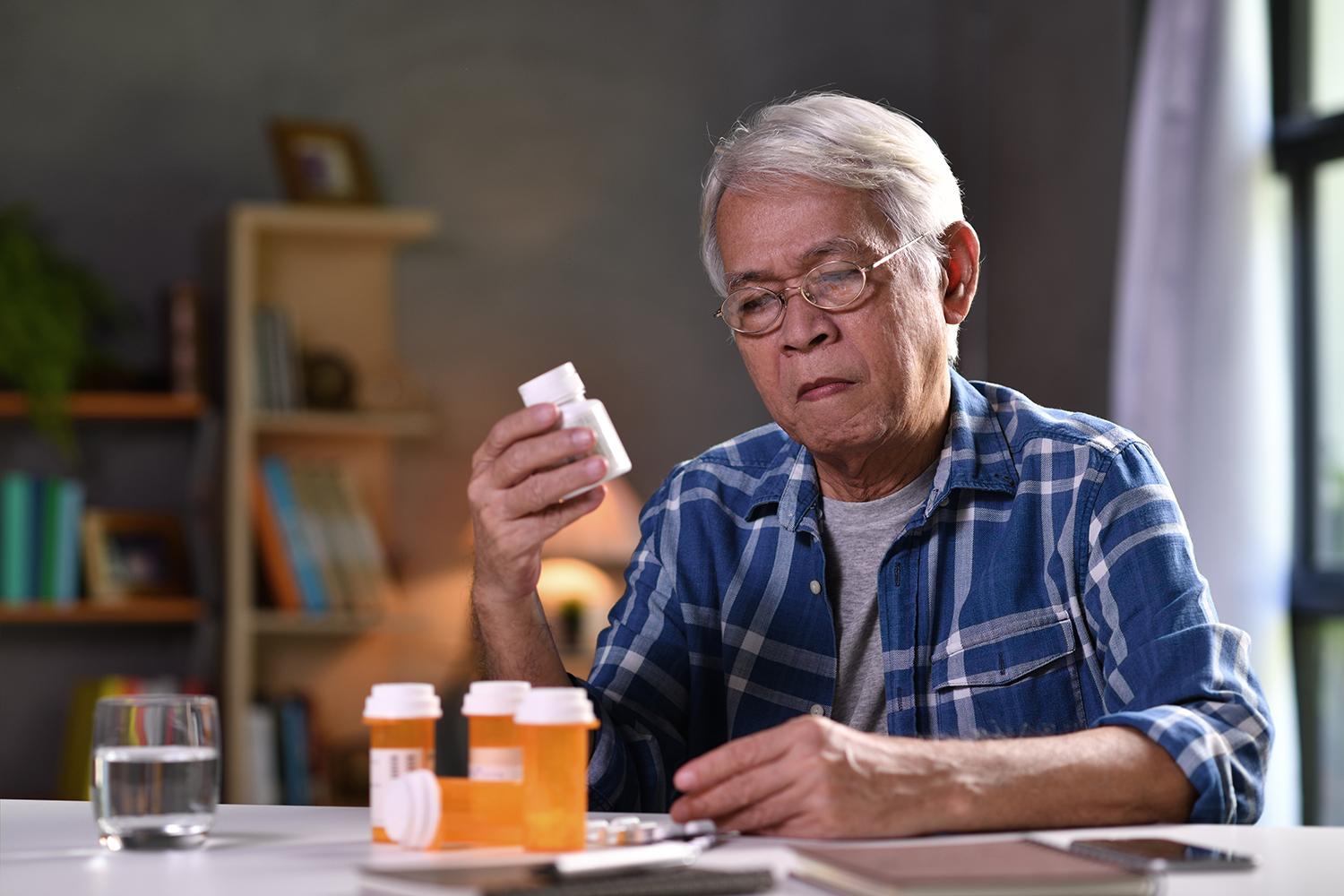 medication expert Old man looking at the details written on medicine bottle