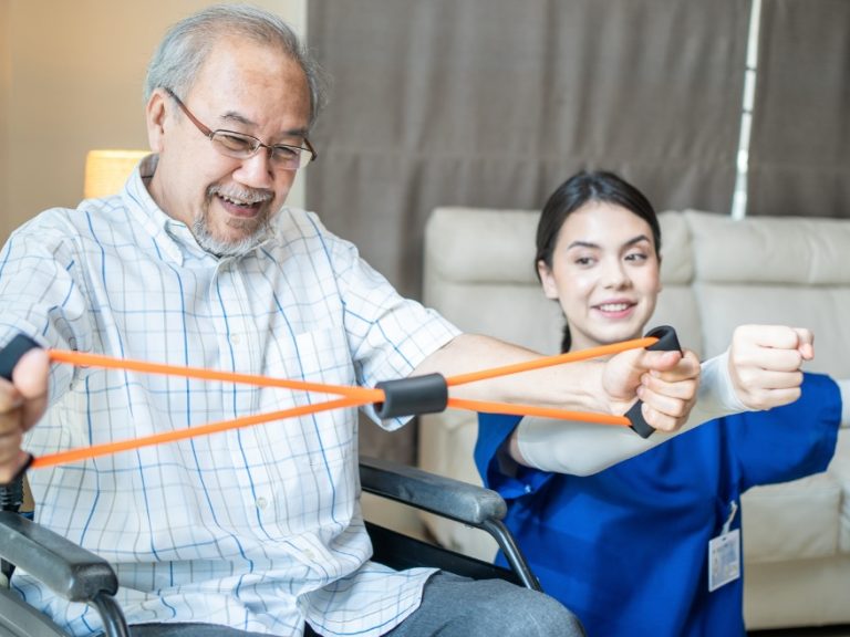 Caregiver girl instructing an old man with stretching exercise